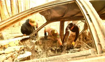  ?? — AFP photo ?? Yuba and Butte County Sheriff officers discover bone fragments inside a burned vehicle in Concow, California after the Camp fire ripped through the area.