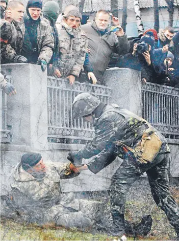  ?? FOTO: REUTERS ?? Un guardia del ministerio de Defensa de Ucrania, trata de arrestar a un miembro del batallón Aydar que entró a las dependenci­as de la cartera durante una protesta ayer en Kiev.
