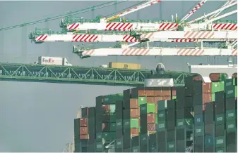  ?? DAMIAN DOVARGANES, THE ASSOCIATED PRESS ?? Transport trucks cross the Vincent Thomas Bridge as shipping containers are seen stacked at the Evergreen terminal at the Port of Los Angeles in San Pedro, California. Contract talks between workers at 29 U.S. West Coast ports and shipping companies are to begin next week.