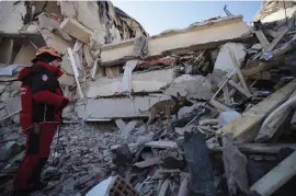  ?? AP ?? SEARCHING THE RUBBLE: A rescuer with a dog searches for people buried under the rubble of a collapsed building after an earthquake struck Elazig, eastern Turkey, on Saturday.