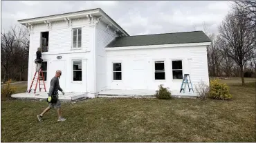  ?? ERIC SEALS — DETROIT FREE PRESS VIA AP ?? Workers for Especially Windows and Remodeling in Highland install new windows at the Banks-dolbeer-bradley-foster Farmhouse in Walled Lake on March 24. The home was an Undergroun­d Railroad stop for slaves to get food and a place to rest during their escape.