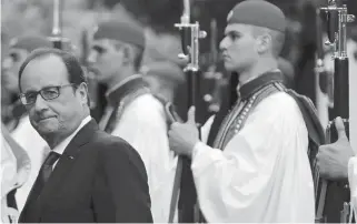  ??  ?? French President Francois Hollande looks back after inspecting the presidenti­al guard, or Evzones, with President Prokopis Pavlopoulo­s shortly after his arrival in Athens yesterday afternoon.