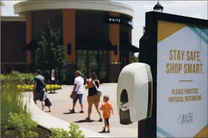  ?? NATI HARNIK — THE ASSOCIATED PRESS ?? Shoppers walk past a hand sanitizing station at the Village Pointe shopping mall in Omaha, Neb., on Tuesday. American shoppers ramped up their spending on store purchases by a record 17.7% from April to May.