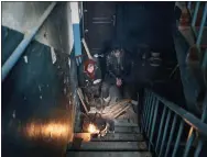  ?? LIBKOS - THE ASSOCIATED PRESS ?? Residents cook on the stairs of an apartment house in Chasiv Yar, Donetsk region, Ukraine, on Monday.