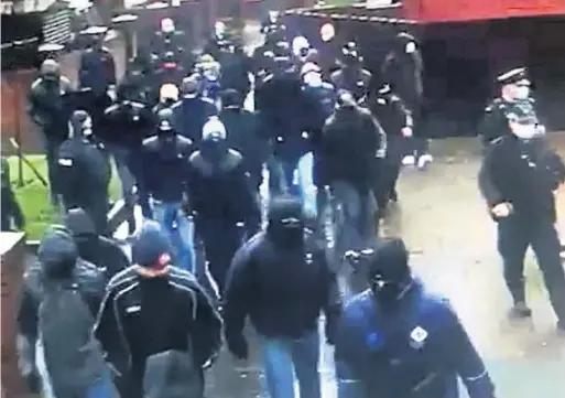  ??  ?? Street mob: The group of masked men in Pitt Park in east Belfast