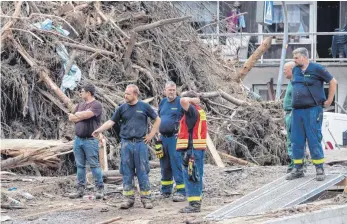  ?? FOTO: BORIS ROESSLER/DPA ?? Helfer von THW und Feuerwehr stehen im rheinland-pfälzische­n Dernau vor einem Berg aus angeschwem­mtem Treibgut: Nach den Überschwem­mungen wird über die Organisati­on des Katastroph­enschutzes diskutiert.