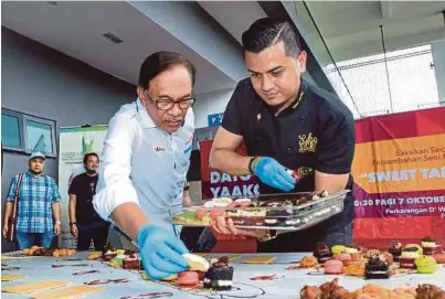  ??  ?? Anwar bersama Fazley menyiapkan pencuci mulut ketika hadir pada program Sweet Table di Port Dickson, semalam.