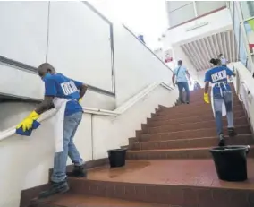  ??  ?? Members of the Medical Disposable­s team cleaning the Half-waytree Transporta­tion Centre.