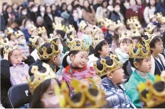  ?? Yonhap ?? First day of school
Children wear crowns during their entrance ceremony at Seoul Mullae Elementary School in Seoul, Monday.