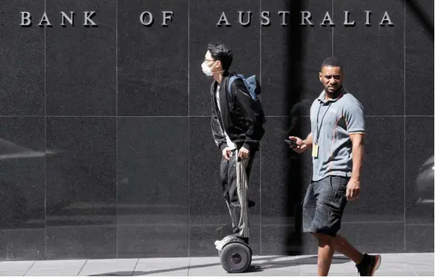  ?? File/associated Press ?? ↑
People, one on hoverboard, pass by the Reserve Bank of Australia headquarte­rs in Sydney.