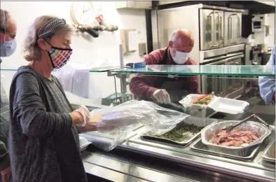  ?? Christian Abraham / Hearst Connecticu­t Media ?? Sandy Mehl, a volunteer from Temple Sinai, bags a take-out Christmas dinner for guests at New Covenant Center in Stamford on Friday.