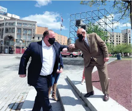  ?? MARK MORAN/THE CITIZENS’ VOICE VIA AP ?? Wilkes-Barre Mayor George Brown, right, bumps elbows with Troy Standish before the start of an event last week on Public Square in Wilkes-Barre, Pa. The banner raising was a socially distanced public “thank you” to frontline and essential workers in the face of the COVID-19 pandemic.