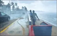  ?? HECTOR RETAMAL / AGENCE FRANCE-PRESSE ?? A man and his daughter flee from the rain on a beach in San Juan, Puerto Rico, on Tuesday, before the arrival of Hurricane Maria.