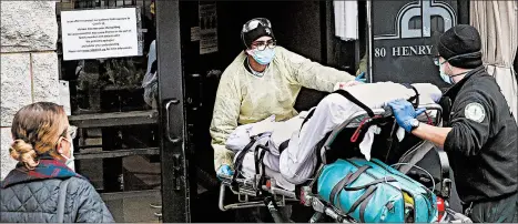  ?? JOHN MINCHILLO/AP ?? Emergency medical workers wheel a patient in April into the Cobble Hill Health Center by in the Brooklyn borough of New York City.