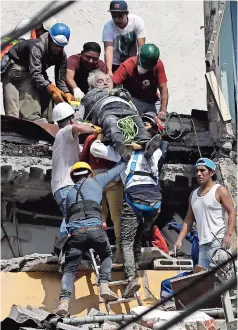  ??  ?? CIUDADANOS RESCATAN a una persona de entre los escombros de un edificio