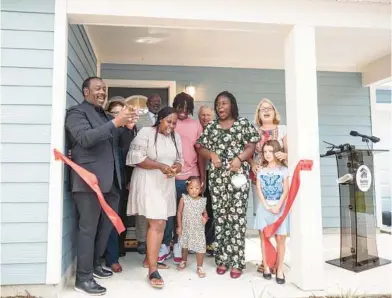  ?? WILLIE J. ALLEN JR./ORLANDO SENTINEL ?? Keetonia Wilson, center, cuts the red ribbon as Orange County Mayor Jerry Demings, left, Wilson’s children, Apopka city officials and Habitat for Humanity members watch during the opening of her home in Apopka on Saturday.