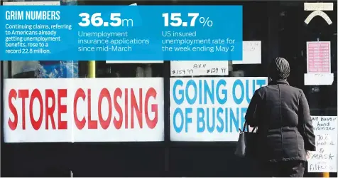  ?? AP ?? A woman looks at signs at a store closed due to Covid-19 in Niles, Illinois. Initial jobless claims in state programmes totalled 2.98 million in the week ended May 9, the Labour Department said yesterday.