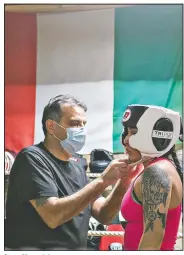  ??  ?? Steve Mazzarisi helps student Lesley Cadenas-Garcia with her headgear at the start of a sparring session. Mazzarisi founded Gladiator Boxing Club of Sterling in March 2020 and built this garage to not only help his son continue his path in boxing but to offer lessons to local youths.