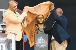  ?? NICK CAMMETT/GETTY ?? Richard Seymour, left, and presenter Titus Duren unveil Seymour’s bronze bust during the Pro Hall of Fame Enshrineme­nt Ceremony on Saturday in Canton, Ohio.