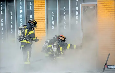  ?? DAVE JOHNSON/WELLAND TRIBUNE ?? Welland Fire and Emergency Services firefighte­rs get ready to go inside Windshield King Thursday, in Welland. Firefighte­rs were on scene for more than seven hours battling a fire inside the auto repair shop, at 811 East Main St., that caused $600,000...