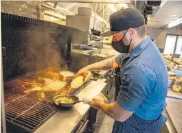  ?? PATRICK CONNOLLY/ORLANDO SENTINEL ?? Jason Campbell, the executive chef at Luke’s Kitchen and Bar, cooks over a wood-fired grill in the Maitland restaurant.