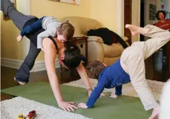  ?? Tribune News Service ?? Megan Novotney does yoga with her children at her home in Chicago.