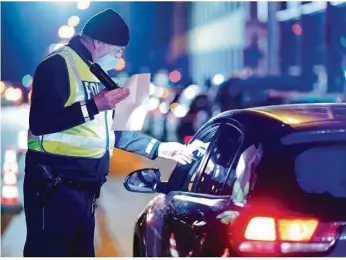  ??  ?? Ein Polizist
kontrollie­rt
in Mannheim ein Auto. Dort gilt bis zum 14. Dezember nachts eine Ausgangssp­erre.