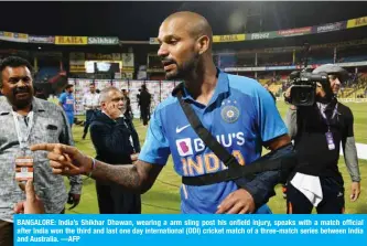  ?? —AFP ?? BANGALORE: India’s Shikhar Dhawan, wearing a arm sling post his onfield injury, speaks with a match official after India won the third and last one day internatio­nal (ODI) cricket match of a three-match series between India and Australia.