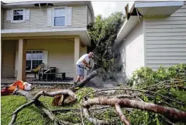  ?? PHOTOS BY BRUCE R. BENNETT / THE PALM BEACH POST ?? Broward sheriff’s Deputy Erica Chace’s neighbor uses a chain saw to clear debris Monday morning at her home on 74th Street North. Her home had extensive roof damage and the fascia on the home’s front was pulled away.