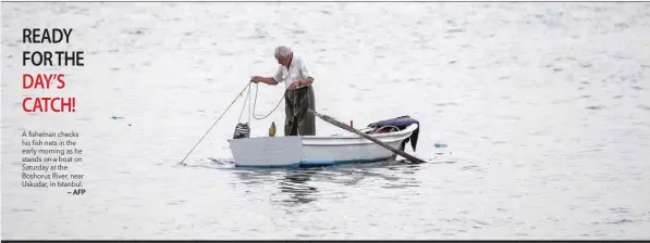  ?? — AFP ?? A fisheman checks his fish nets in the early morning as he stands on a boat on Saturday at the Boshorus River, near Uskudar, in Istanbul.