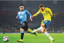  ?? AP ?? Brazil’s Neymar (right) takes a shot as Uruguay’s Lucas Torreira looks on during the friendly at Emirates Stadium.