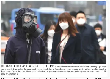  ?? — AFP photo by Jung Yeon-je ?? A South Korean environmen­tal activist (left) wearing a gas mask stands in protest demanding the government to ease air pollution at Gwanghwamu­n square during heavily polluted weather in central Seoul. South Korean President Moon Jae-in had ordered his government to discuss joint dust-reducing measures with China.