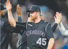  ?? David Zalubowski, The Associated Press ?? Rockies’ relief pitcher Scott Oberg is congratula­ted after the team’s 5-4 win over the San Francisco Giants on Friday nigh.