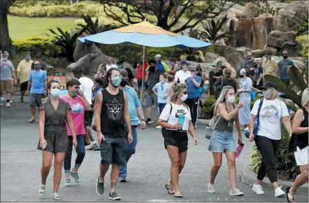  ?? THE ASSOCIATED PRESS ?? Guests wearing masks stroll through SeaWorld as it reopened with new safety measures in place June 11, in Orlando, Fla. The park had been closed since mid-March to stop the spread of the new coronaviru­s.