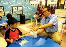 ?? — Bernama photo ?? Abd Latiff (right) applies hand sanitiser on a student, Faruq Faruqi Mohd Fitri during his visit to Bunga Raya Kemas Kindergart­en and Child Care Centre at Presint 11 in Putrajaya.