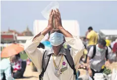  ?? NUTTHAWAT WICHEANBUT ?? A man raises a pack of rice seeds over his forehead and prays. Seeds from the ceremony are seen as sacred by many Thais.