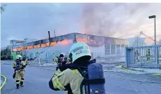  ?? FOTO: TOBIAS DUPKE ?? Ein Foto von Sonntagabe­nd: Einsatzkrä­fte nähern sich unter Atemschutz der brennenden Lagerhalle.