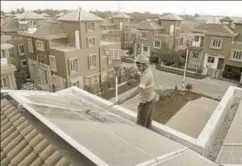  ?? AFP ?? ▪ A worker cleans solar panels at a housing complex near Kolkata. Electrical demand reduction needs to be supported by generation from green sources.