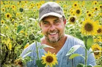  ??  ?? Owner Stefan Harbonis kneels in his sunflower patch on his You Farm property. The farm offers plots for rent to grow fresh produce.