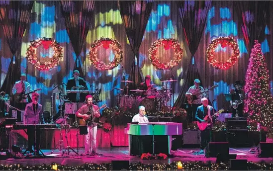  ?? Gina Ferazzi Los Angeles Times ?? BRIAN WILSON, seated at the piano, sings hits from the Beach Boys 1964 Christmas album with his modern-day band at the Fred Kavli Theatre in Thousand Oaks.