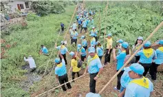  ??  ?? King’s volunteers wearing blue caps and yellow foulards clean a canal in Bangkok.