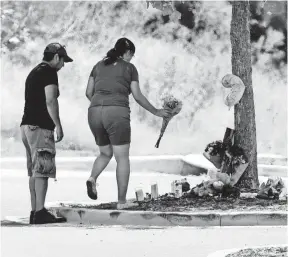  ?? ERIC GAY, AP ?? A couple visit a makeshift memorial in a Walmart parking lot near the site where authoritie­s discovered a tractor-trailer packed with immigrants, several of whom died.