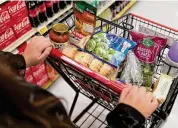  ?? ?? A shopper pushes a cart of groceries at a supermarke­t in Bellflower, Calif., in February 2023.