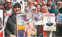  ?? AFP ?? Protesters hold portraits of Palestinia­n prisoners during a rally in the West Bank city of Ramallah to show their support to inmates’ hunger strike in Israeli jails.