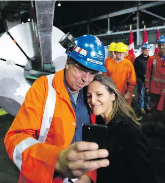 ?? PETER POWER / THE CANADIAN PRESS FILES ?? Global affairs minister Chrystia Freeland, seen taking a picture with a Stelco area manager in Hamilton, Ont., in June, has maintained that the modernizat­ion of NAFTA and the steel and aluminum dispute were separate issues. Yet the new deal shows that is not the case, John Ivison writes.