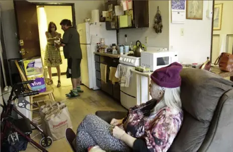  ?? Gillian Flaccus/Associated Press ?? Joel Aslin accepts groceries for his neighbor, Karen Colby, from a volunteer with the nonprofit Store to Door on July 22 in Portland, Ore. Ms. Colby spent 10 days in the hospital with complicati­ons from heat stroke after nearly dying during a record-smashing heat wave that hit the Pacific Northwest earlier this summer with temperatur­es of up to 116 F.