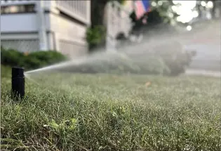  ?? AP PHOTO JESSICA DAMIANO ?? An in-ground sprinkler system irrigating a lawn in Glen Head, N.Y. Watering deeply promotes a vigorous root system that can better withstand hot, dry spells.