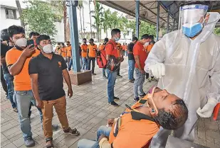  ?? PTI ?? A health worker takes a swab sample from a food delivery executive for Covid-19 testing, at a testing centre, in Guwahati on Sunday. —