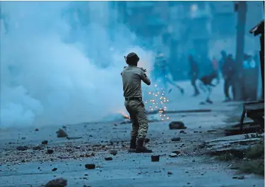  ?? MUKHTAR KHAN THE ASSOCIATED PRESS ?? An Indian police officer launches tear gas on Kashmiri protesters in Srinagar, Indian controlled Kashmir. An Indian tourist was killed during a stone-throwing protest in Kashmir, officials said Tuesday.