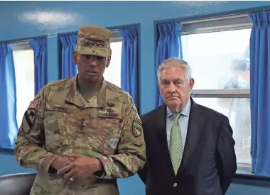  ?? ASSOCIATED PRESS ?? U.S. Secretary of State Rex Tillerson is briefed by U.S. Gen. Vincent K. Brooks as a North Korean soldier takes a photograph through a window Friday at the U.N. Command Military Armistice Commission in the border village of Panmunjom.